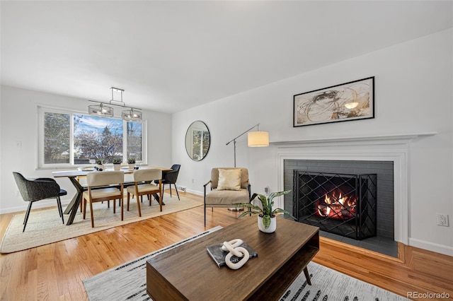 living room with wood-type flooring and a brick fireplace