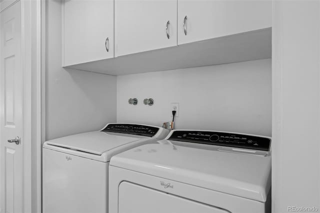 laundry room featuring washer and clothes dryer and cabinets