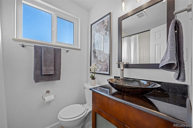 bathroom with walk in shower, vanity, and toilet