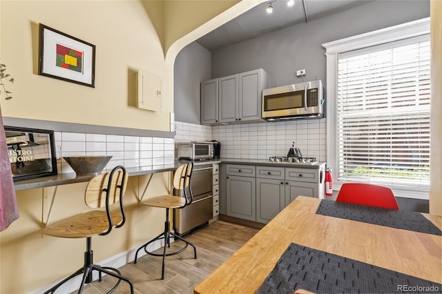 1301 N Ogden St Unit 1A, Denver, CO 80218 - kitchen featuring appliances with stainless steel finishes, light wood-style floors, gray cabinets, backsplash, and wooden counters