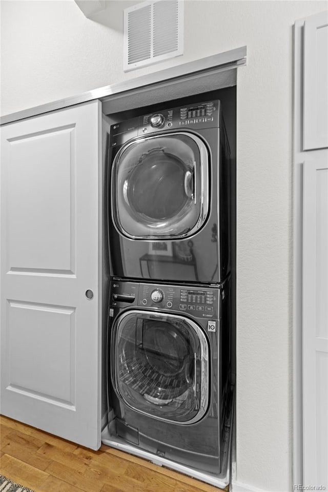 laundry room featuring stacked washer and dryer, laundry area, visible vents, and light wood-style floors