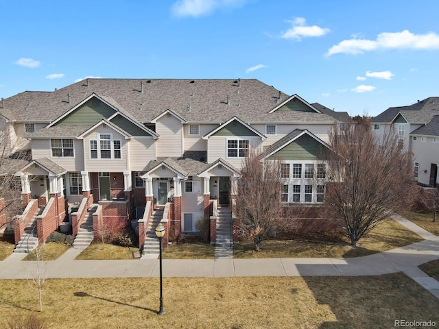 townhome / multi-family property with brick siding, a front lawn, and a residential view