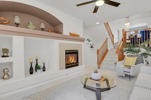 living area with built in shelves, recessed lighting, a ceiling fan, stairway, and a tiled fireplace