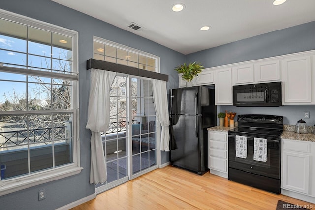 kitchen featuring white cabinets, visible vents, light wood-style flooring, and black appliances