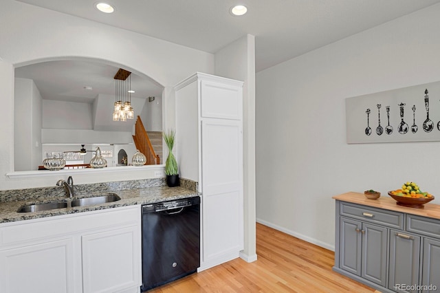 kitchen with black dishwasher, light wood finished floors, recessed lighting, white cabinetry, and a sink