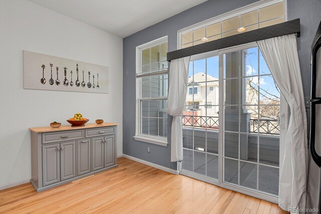 doorway to outside with light wood-type flooring and baseboards