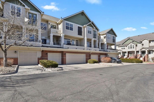 townhome / multi-family property featuring a residential view, brick siding, and an attached garage