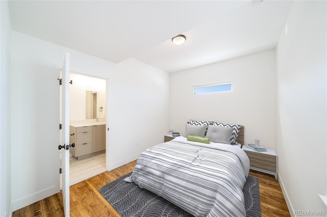 bedroom with ensuite bathroom and light wood-type flooring