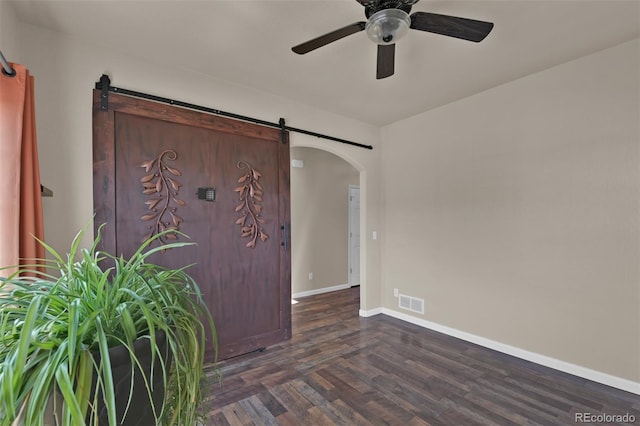 9455 Shinnecock Ct, Peyton, CO 80831 - empty room featuring a barn door, arched walkways, ceiling fan, and wood finished floors