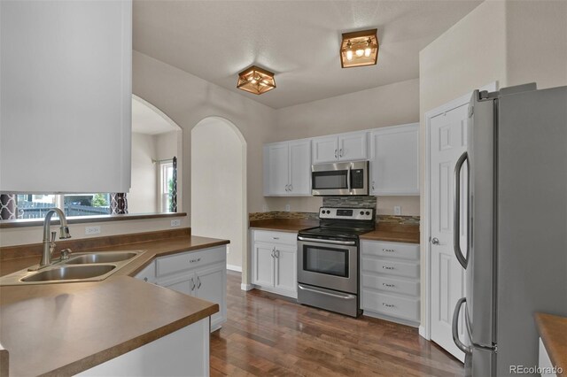 9455 Shinnecock Ct, Peyton, CO 80831 - kitchen with appliances with stainless steel finishes, a sink, dark countertops, white cabinets, and dark wood finished floors