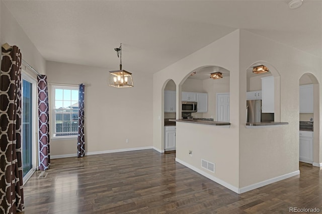 9455 Shinnecock Ct, Peyton, CO 80831 - unfurnished dining area with dark wood-type flooring, baseboards, a chandelier, and arched walkways