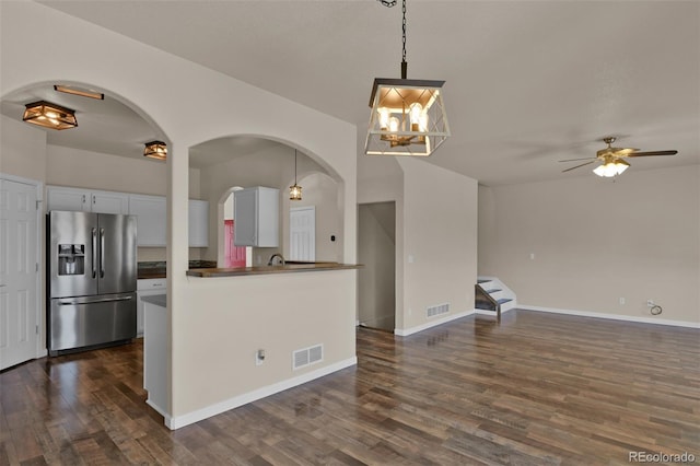 9455 Shinnecock Ct, Peyton, CO 80831 - kitchen with stainless steel fridge, dark countertops, dark wood-type flooring, open floor plan, and arched walkways