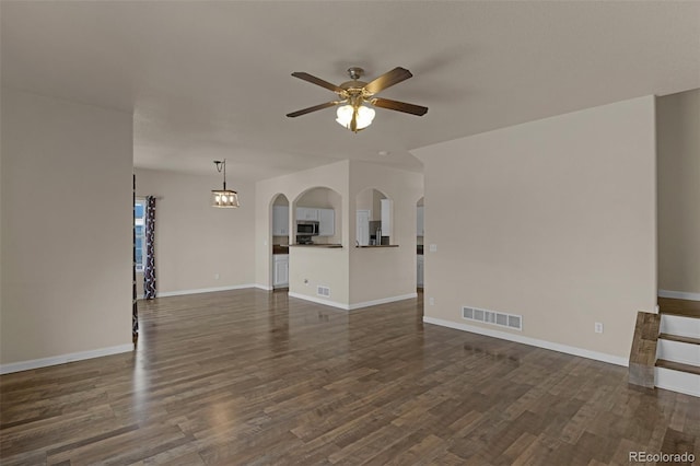 9455 Shinnecock Ct, Peyton, CO 80831 - unfurnished living room with ceiling fan, dark wood-style floors, arched walkways, and baseboards