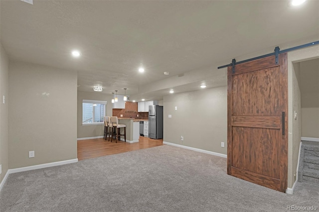9455 Shinnecock Ct, Peyton, CO 80831 - living room featuring light carpet, a barn door, baseboards, and recessed lighting