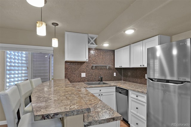 9455 Shinnecock Ct, Peyton, CO 80831 - kitchen featuring appliances with stainless steel finishes, a peninsula, a sink, white cabinets, and a textured ceiling