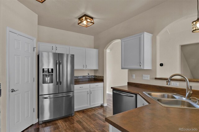 9455 Shinnecock Ct, Peyton, CO 80831 - kitchen featuring appliances with stainless steel finishes, a sink, dark countertops, dark wood-type flooring, and white cabinetry
