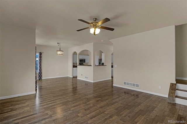9455 Shinnecock Ct, Peyton, CO 80831 - unfurnished living room featuring a ceiling fan, dark wood finished floors, arched walkways, and baseboards