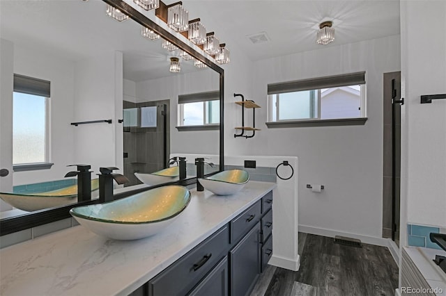 9455 Shinnecock Ct, Peyton, CO 80831 - full bathroom featuring double vanity, healthy amount of natural light, a stall shower, and wood finished floors