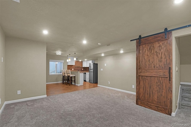 9455 Shinnecock Ct, Peyton, CO 80831 - unfurnished living room with light carpet, a barn door, baseboards, and recessed lighting