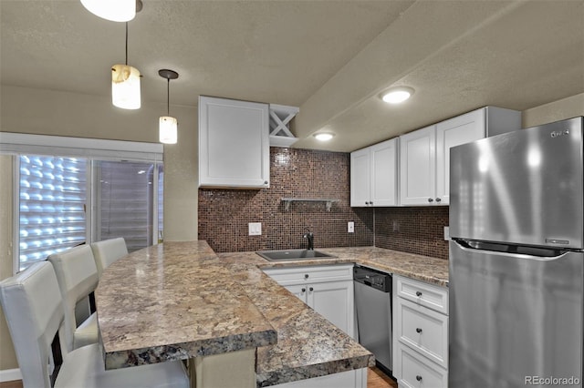 9455 Shinnecock Ct, Peyton, CO 80831 - kitchen with stainless steel appliances, a peninsula, a sink, white cabinets, and a textured ceiling