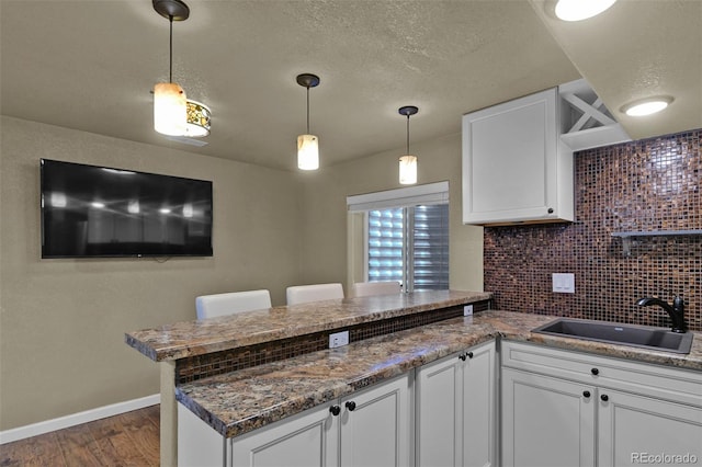 9455 Shinnecock Ct, Peyton, CO 80831 - kitchen featuring a peninsula, a sink, dark wood-type flooring, white cabinets, and a textured ceiling