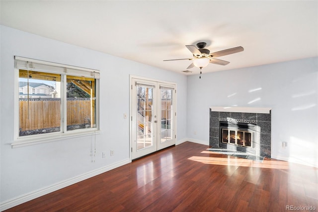 unfurnished living room with plenty of natural light, dark hardwood / wood-style floors, a fireplace, and french doors