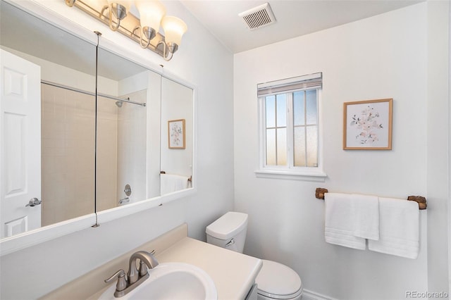 bathroom with a tile shower, vanity, and toilet