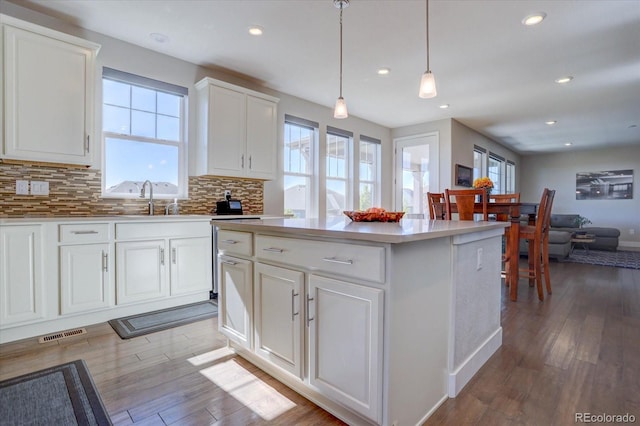 kitchen with hanging light fixtures, backsplash, light hardwood / wood-style floors, and white cabinets