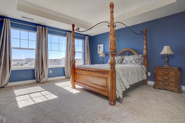 bedroom featuring a tray ceiling, crown molding, and carpet