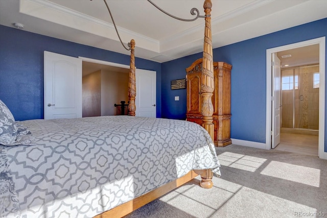 bedroom with a raised ceiling, crown molding, carpet, and connected bathroom