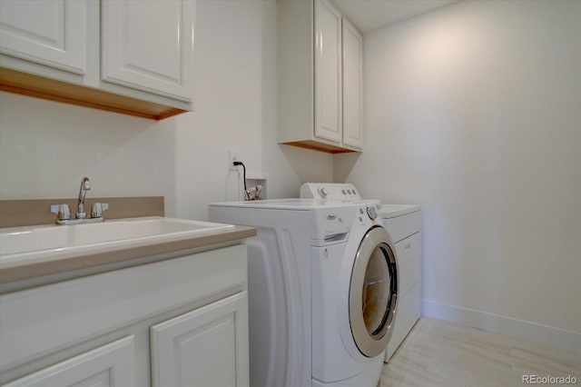 laundry room featuring cabinets, sink, and washer and clothes dryer