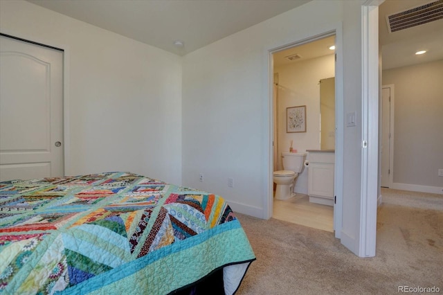 bedroom featuring light carpet and ensuite bath