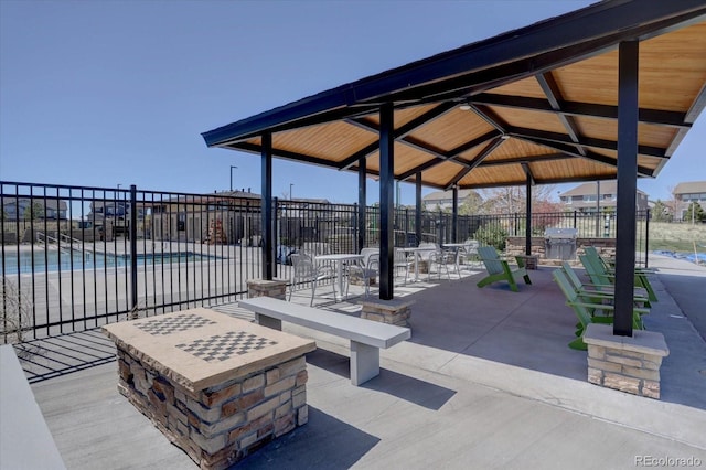 view of patio / terrace with a gazebo, a grill, a community pool, and a fire pit