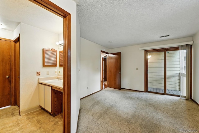 2960 Shadow Creek Dr Unit 201, Boulder, CO 80303 - unfurnished bedroom with a textured ceiling, access to exterior, connected bathroom, and light colored carpet