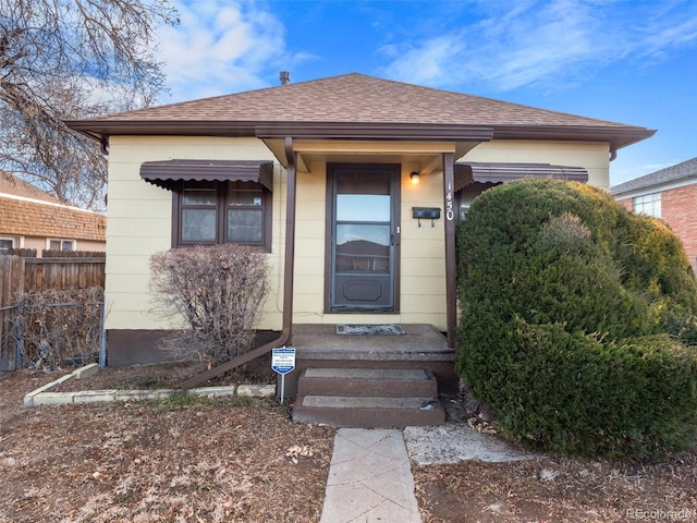 entrance to property with roof with shingles and fence