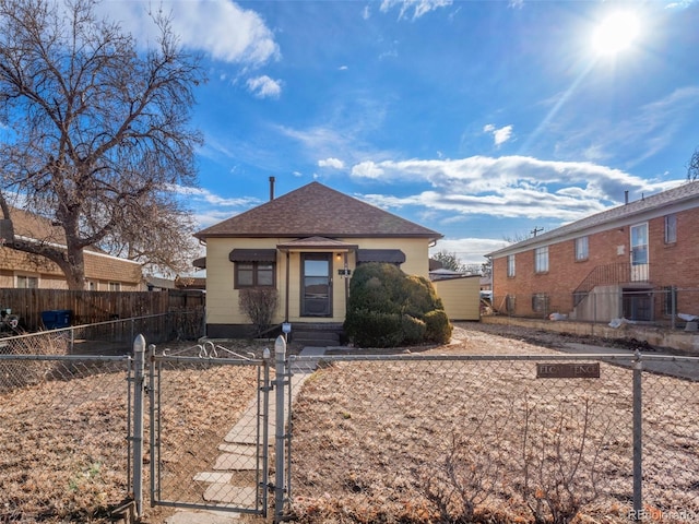 bungalow-style house with a fenced front yard, a gate, and a shingled roof