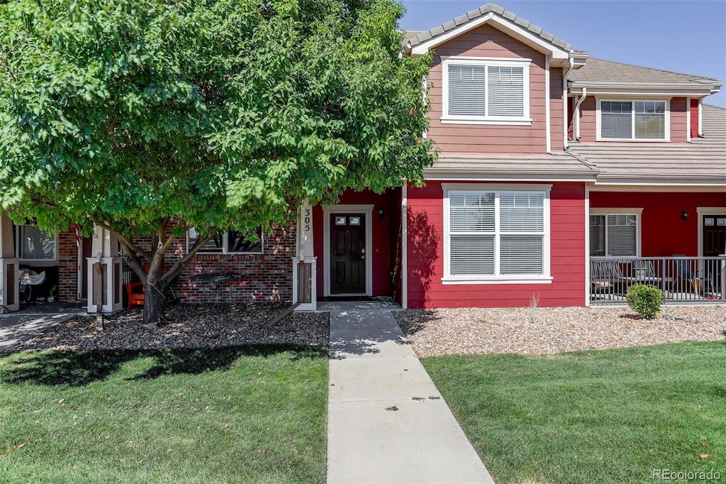 view of front of house with a front lawn, brick siding, and a tile roof