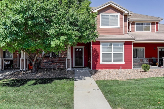 view of front of house with a front lawn, brick siding, and a tile roof