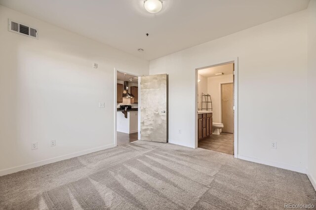 unfurnished bedroom featuring carpet flooring, baseboards, and ensuite bath