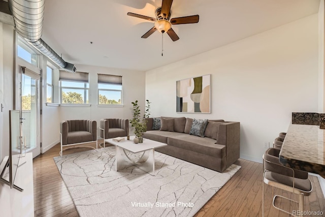 living area with hardwood / wood-style floors, a ceiling fan, and baseboards