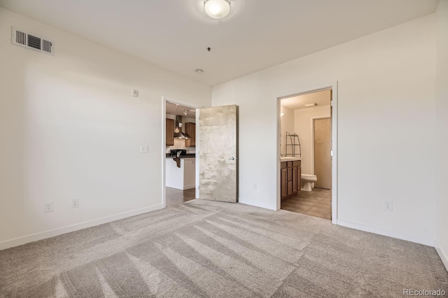 unfurnished bedroom featuring carpet flooring, baseboards, and ensuite bath