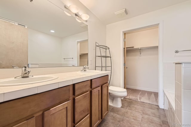 full bath featuring toilet, double vanity, tile patterned flooring, and a walk in closet