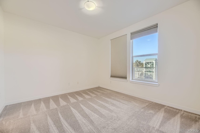 unfurnished room featuring light colored carpet and baseboards