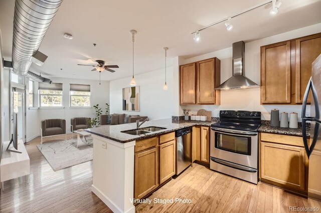 1313 S Clarkson St Unit 205, Denver, CO 80210 - kitchen with appliances with stainless steel finishes, wall chimney range hood, a sink, brown cabinetry, and a peninsula