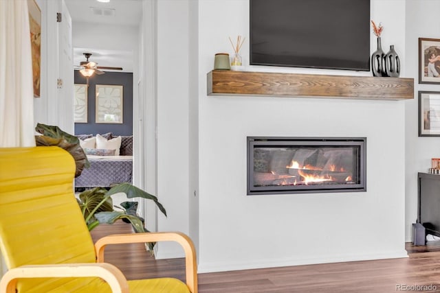 722 Eva Peak Dr, Erie, CO 80516 - sitting room featuring wood finished floors, a ceiling fan, and a glass covered fireplace