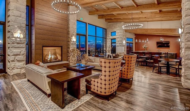 722 Eva Peak Dr, Erie, CO 80516 - living area featuring a chandelier, wood finished floors, a towering ceiling, wood ceiling with exposed beams, and ornate columns