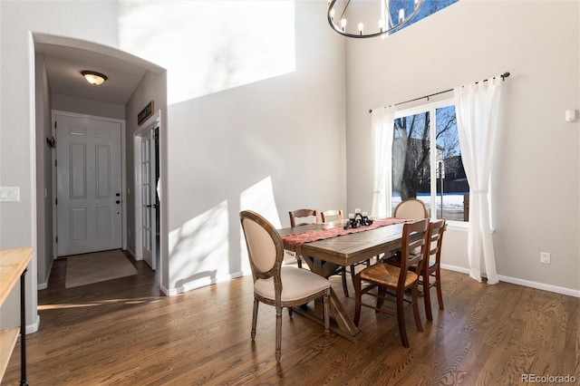 dining space featuring dark wood-type flooring and an inviting chandelier