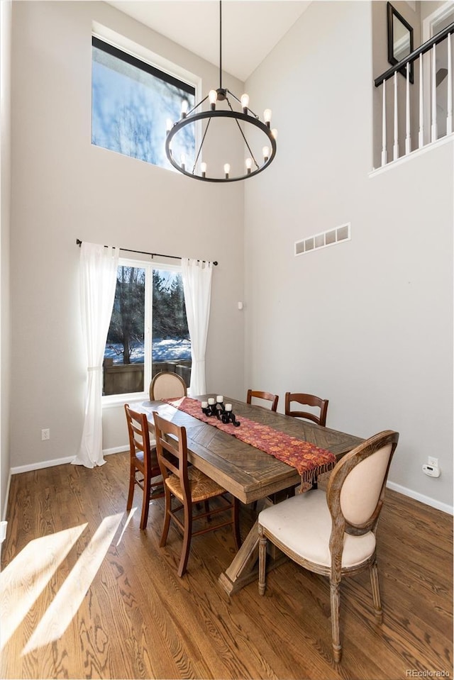 dining area with a towering ceiling, a chandelier, and hardwood / wood-style floors