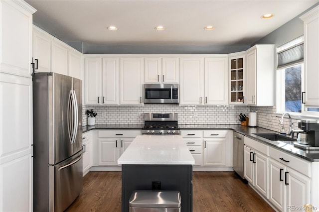 kitchen with appliances with stainless steel finishes, white cabinetry, a kitchen island, and sink