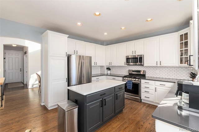 kitchen featuring a center island, decorative backsplash, dark wood-type flooring, stainless steel appliances, and white cabinets